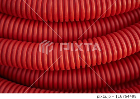 Corrugated for insulation cable of wires underground, plastic tube, electricity protection pipe for construction works, red corrugation close-up with copy space. High quality photo 116764499