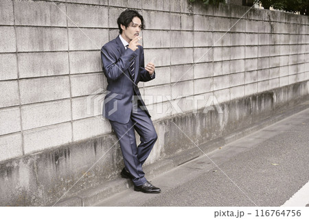 屋外でタバコを吸う男性 116764756