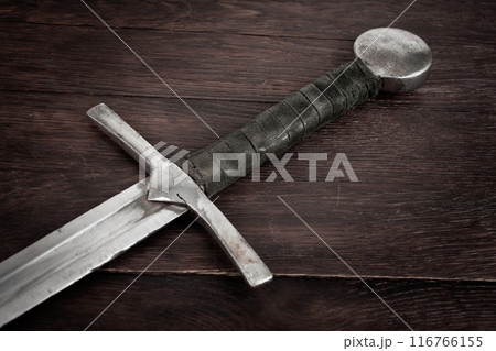 Medieval sword on wooden background. 116766155