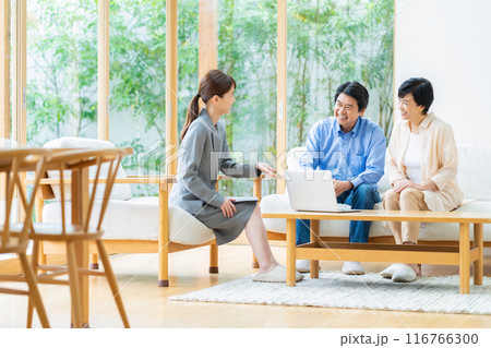 コンサルタントとリビングで商談をするミドルの夫婦 116766300