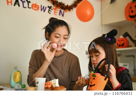 Mother and daughter decorating Halloween cupcakes in the decorated kitchen Mother and daughter decorating Halloween cupcakes in the decorated kitchen 116766831