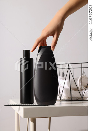 Bottle with men's cosmetics, hand and basket with towels on table on white background Bottle with men's cosmetics, hand and basket with towels on table on white background 116767208