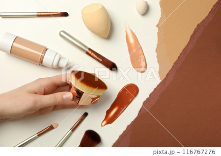 Bottle with foundation, brushes and hand on white background, top view Bottle with foundation, brushes and hand on white background, top view 116767276