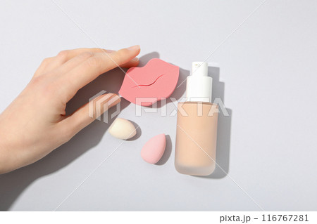 Bottle with foundation, female hand and cosmetic sponges on white background, top view 116767281