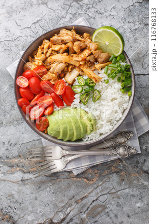 Mexican rice bowl with chicken carnitas, cherry tomatoes, avocado, peppers close-up. Vertical top view Mexican rice bowl with chicken carnitas, cherry tomatoes, avocado, peppers close-up. Vertical top view 116768133