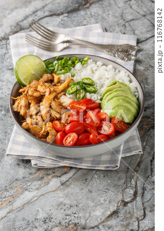 Mexican rice bowl with chicken carnitas, cherry tomatoes, avocado, peppers close-up. Vertical 116768142