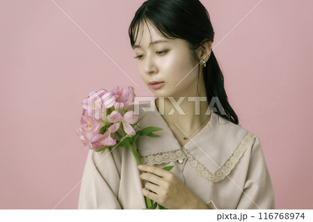 ピンク背景の花を持つ若い女性のポートレート ピンク背景の花を持つ若い女性のポートレート 116768974