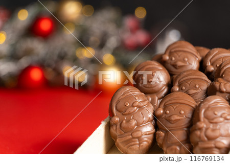 Chocolates in the shape of Christmas figures on the background of a flashing garland 116769134