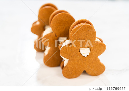 Gingerbread cookies filled with eggnog buttercream stand out, their rich hue complementing the eggnog buttercream, against a gentle background. These festive treats exude a homemade allure. 116769435