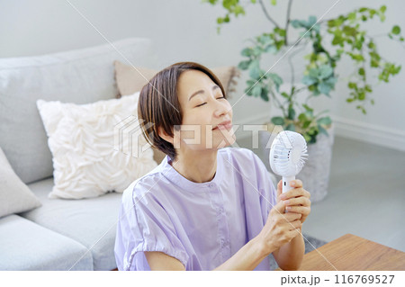 リビングで携帯扇風機を使う女性 リビングで携帯扇風機を使う女性 116769527
