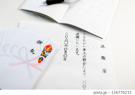 白い机の上に準備された手書きの退職届とお礼用ポチ袋と新しいスケジュール帳 116770232