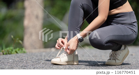 Woman Tying Shoelaces in Outdoor Park, Ready for Exercise in Athletic Wear and Sneakers Woman Tying Shoelaces in Outdoor Park, Ready for Exercise in Athletic Wear and Sneakers 116770451