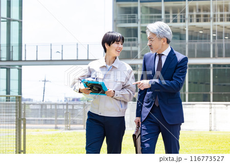 施設の外を歩きながら会話するビジネスマンとエンジニア 施設の外を歩きながら会話するビジネスマンとエンジニア 116773527