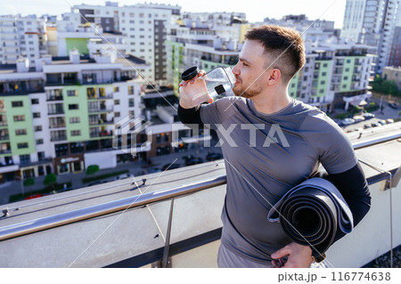 Young fit sports man making break and drinking water after workout on rooftop with city view outdoor. Young fit sports man making break and drinking water after workout on rooftop with city view outdoor. 116774638
