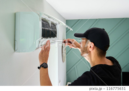 Air conditioner maintenance. Male technician repairing cooling system Air conditioner maintenance. Male technician repairing cooling system 116775631