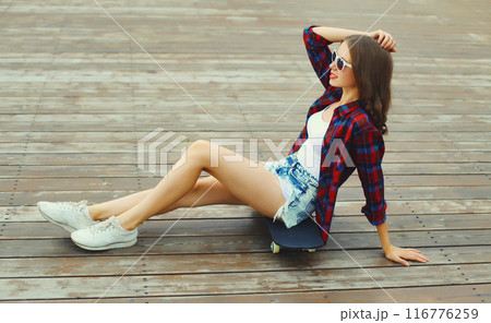 Stylish young woman with skateboard in casual clothes, modern teenage girl posing in the city 116776259