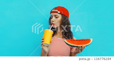 Summer portrait of young woman drinking juice with juicy slice watermelon fruit on blue background Summer portrait of young woman drinking juice with juicy slice watermelon fruit on blue background 116776284