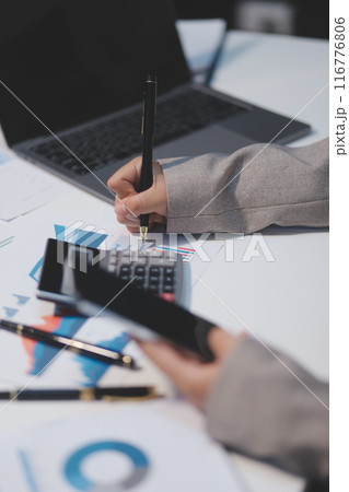 Business woman using calculator and writing make note with calculate. Woman working at office with laptop and documents on his desk Business woman using calculator and writing make note with calculate. Woman working at office with laptop and documents on his desk 116776806