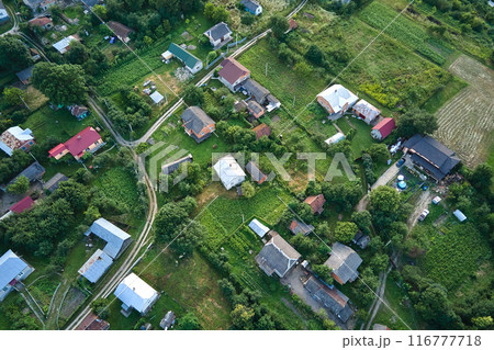 Aerial landscape view of village houses and distant green cultivated agricultural fields with growing crops on bright summer day Aerial landscape view of village houses and distant green cultivated agricultural fields with growing crops on bright summer day 116777718