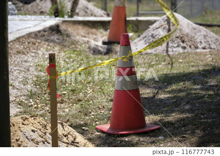 Yellow warning cones and tape as protective restriction barrier at industrial construction site. Safety for pedestrians 116777743