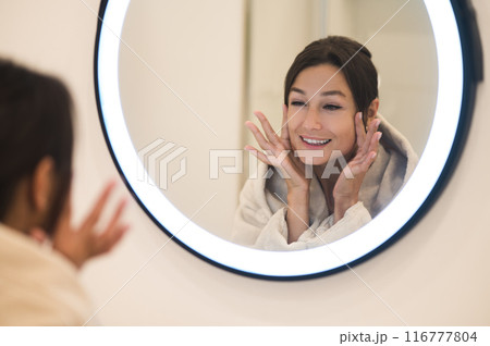 Cute caucasian dark-haired woman at the mirror in the bathroom 116777804