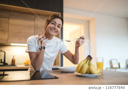 Young woman in casual clothes spending time at home and having breakfast 116777840