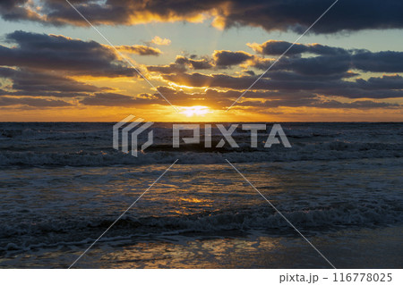 Ocean sunset landscape with soft evening sea water waves crushing on sandy beach 116778025