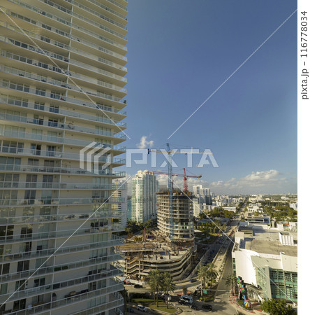 New construction site of developing residense in american urban area. Industrial tower lifting cranes in Miami, Florida. Concept of housing growth in the USA New construction site of developing residense in american urban area. Industrial tower lifting cranes in Miami, Florida. Concept of housing growth in the USA 116778034