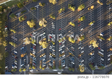 Large parking lot with many parked cars. Big carpark at supercenter shopping mall with lines and markings for vehicle places and directions 116778070