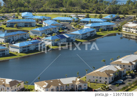 Hurricane damaged apartment buildings rooftops covered with protective plastic tarp against rain water leaking until replacement of asphalt shingles. Aftermath of natural disaster 116778105