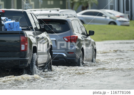 Hurricahe rainfall flooded Florida road with evacuating cars and surrounded with water houses in suburban residential area Hurricahe rainfall flooded Florida road with evacuating cars and surrounded with water houses in suburban residential area 116778106