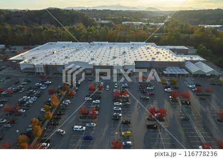View from above of american grocery store with many parked cars on parking lot with lines and markings for parking places and directions. Place for vehicles in front of a strip mall center 116778236