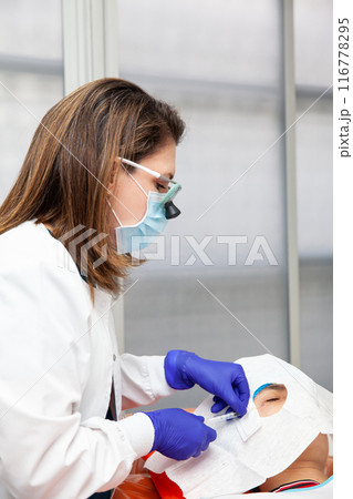 Skin lesion removal procedure. Dermatologist carrying out a removal of benign skin lesion on the face of a young male patient. 116778295