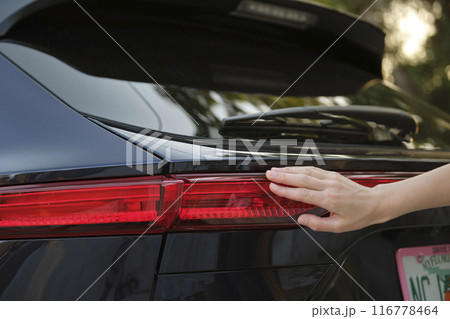 Close-up of human hand on rear car stoplight, checkout before driving. Safety travel concept 116778464