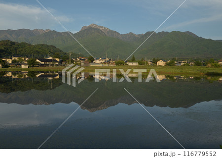 北杜市白州町の街並みや南アルプスの山並みを映す田植え前の田んぼ 116779552