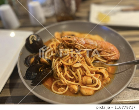 Spaghetti with mussels and shrimp in a plate on a wooden table at Malta restaurant. 116779717