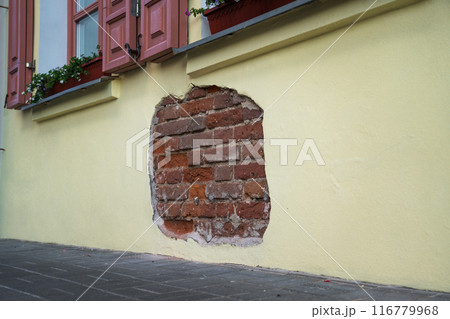 The fallen plaster from the wall of the building from under which the brickwork is visible The fallen plaster from the wall of the building from under which the brickwork is visible 116779968