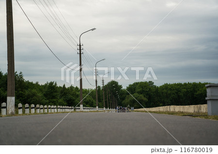 The road leading into the distance. The road along the sea where people walk. Lampposts along the road The road leading into the distance. The road along the sea where people walk. Lampposts along the road 116780019