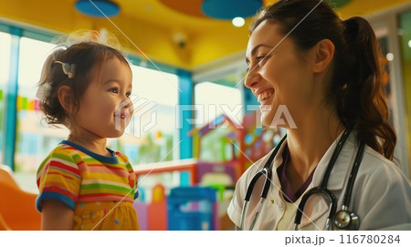 Pediatric doctor with a warm smile attending to a young child in a colorful clinic environment 116780284