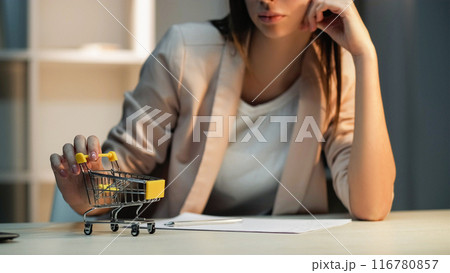 Lazy employee. Shopping daydream. Unhappy bored female office worker procrastinating playing toy delivery cart at workplace wishing purchase. Lazy employee. Shopping daydream. Unhappy bored female office worker procrastinating playing toy delivery cart at workplace wishing purchase. 116780857