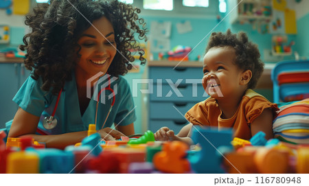 A nurse in a pediatric room bonds with a toddler by playing and caring for them 116780948