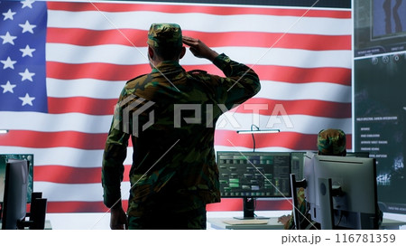 American military personnel supervising cyber warfare activity in high tech office, top secret intelligence on big screen. Governmental experts manage hybrid war, conflict prevention. Camera A. 116781359