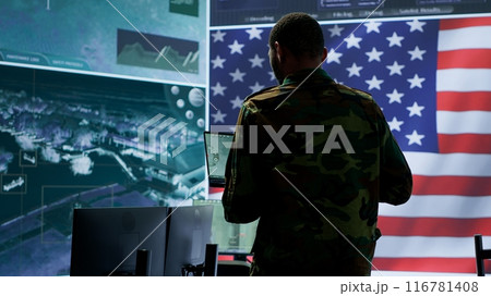 Professionals in US military uniforms operate computers and big screen, working on surveillance and intelligence to ensure national security from a high tech control center. Camera A. Professionals in US military uniforms operate computers and big screen, working on surveillance and intelligence to ensure national security from a high tech control center. Camera A. 116781408