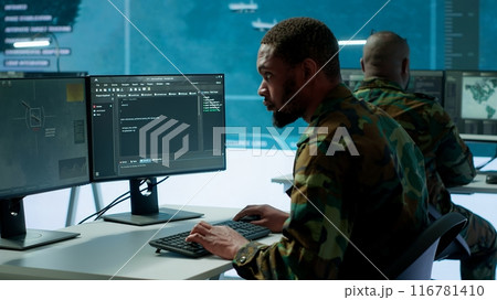 IT expert monitors AI brain intelligence system to collect crucial real time data for a new defense military operation on pc in command post. Security protocols for an intense mission. Camera A. 116781410
