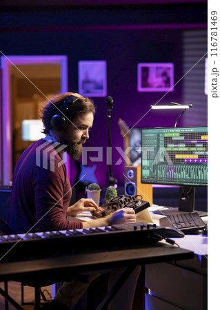 Sound engineer editing audio recordings with daw software and mixing console, adjusting volume levels on amplifier. Artist mixing and mastering soundtracks, operating pre amp knobs. Sound engineer editing audio recordings with daw software and mixing console, adjusting volume levels on amplifier. Artist mixing and mastering soundtracks, operating pre amp knobs. 116781469