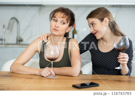 Sad woman sits silently in kitchen, friend sympathize and comfort her 116783765