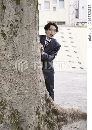 木の影からこっそり覗く男性 116783817