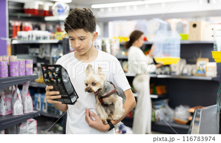 Teenager with Yorkshire terrier choosing dry dog food in pet store Teenager with Yorkshire terrier choosing dry dog food in pet store 116783974