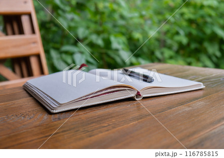 Empty white open paper notebook in wooden table outdoors in garden. Concept of self reflection discovery journal, writing gratitude 116785815