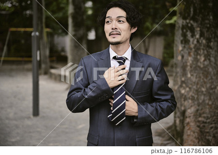 屋外にいる表情豊かなスーツ姿の男性 116786106